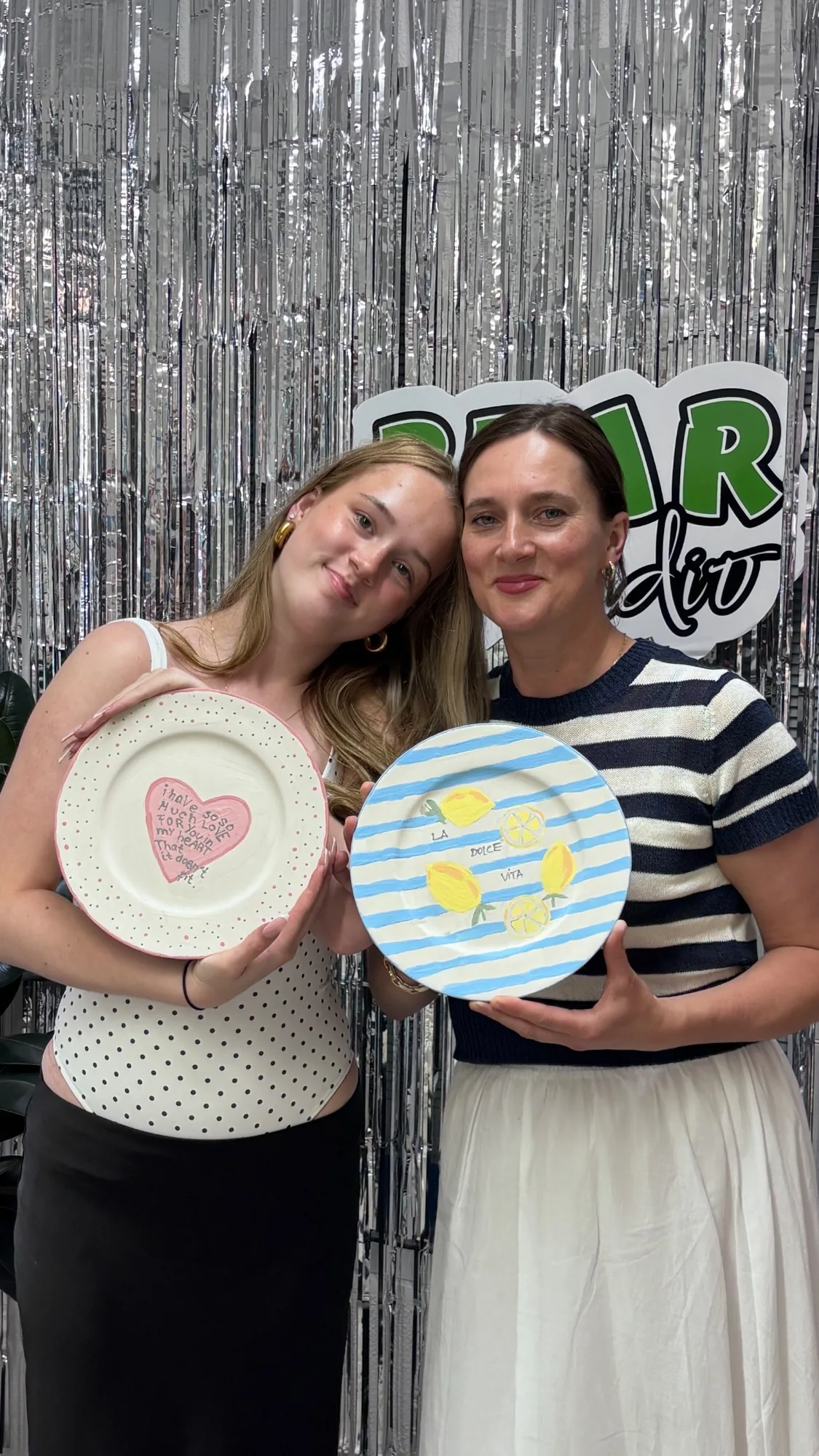 Two adult visitors presenting their painted ceramic plates